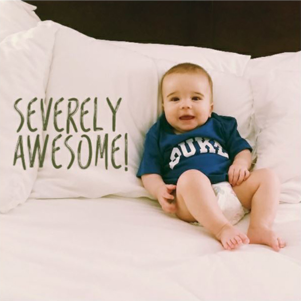 gabe as a baby wearing a duke shirt lounging on the bed
